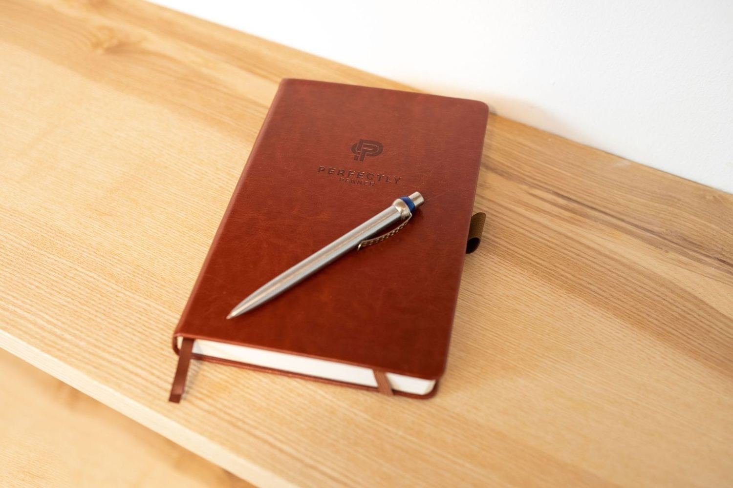 A leather diary with a pen on a desk